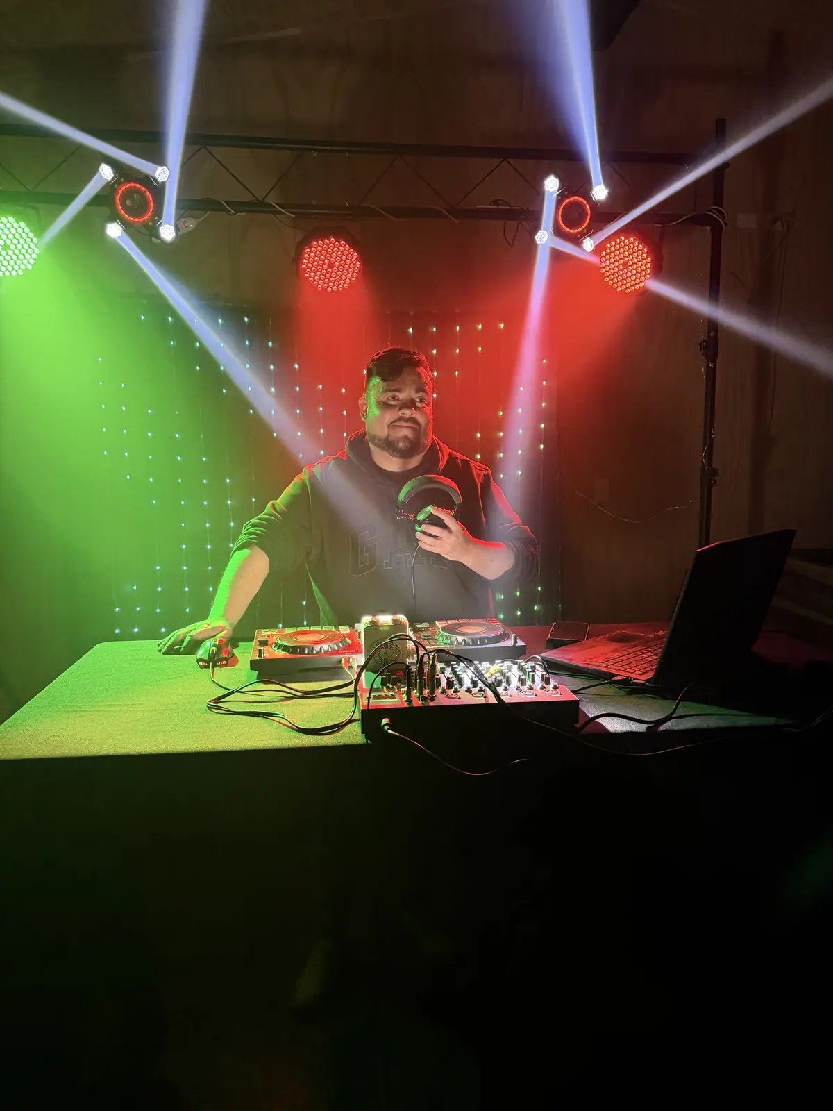 DJ en la cabina con luces robóticas verdes