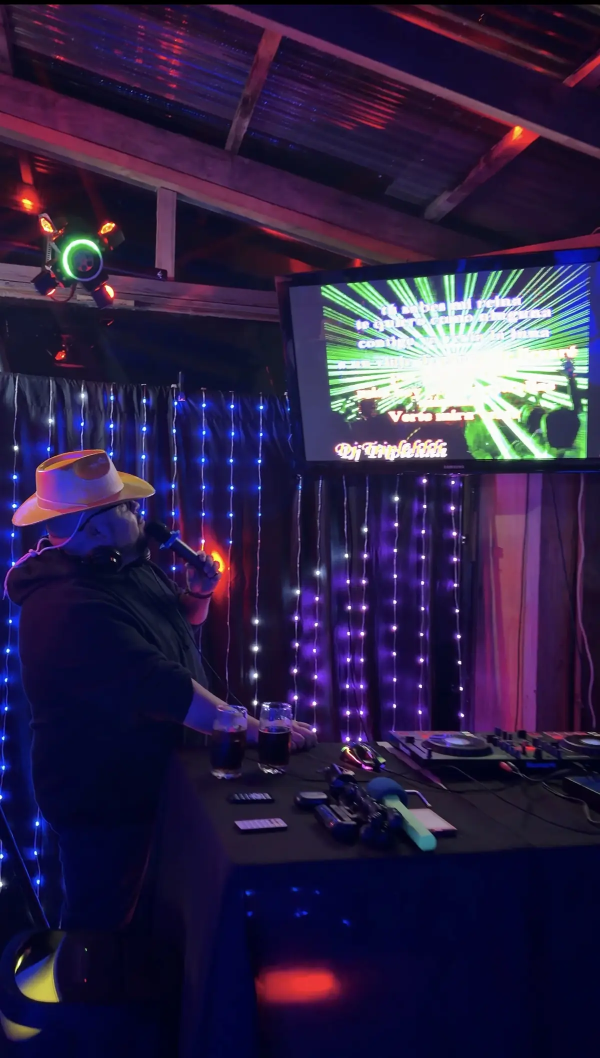 Micrófono y sombrero en la cabina de un local, con pantalla de karaoke