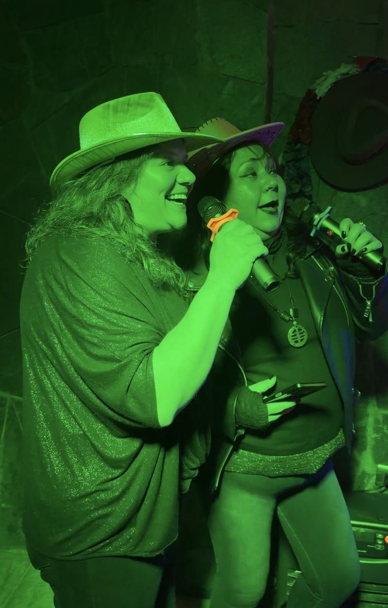 Dos invitadas cantando karaoke con micrófono